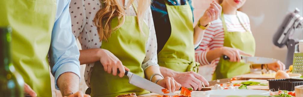 People in aprons slicing vegetables